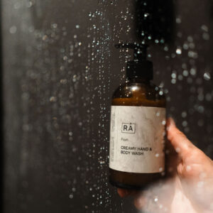 favn creamy hand and body wash holdes av en hånd under rennende vann i dusjen