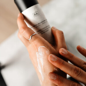 kvinne smører hendene med rå skincare favn extra nourishing cream