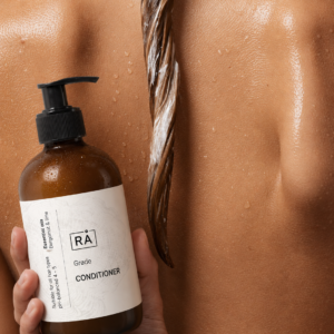Kvinne sett bakfra med balsam i år skincare grøde balsam i håret. Hun holder balsamen i hånden