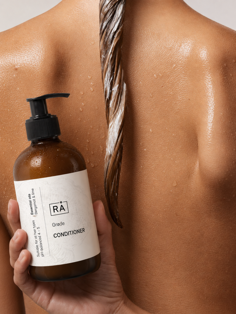 Kvinne sett bakfra med balsam i år skincare grøde balsam i håret. Hun holder balsamen i hånden