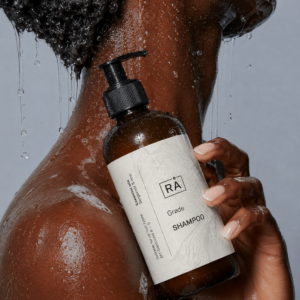 Kvinne holder RÅ Skincare grøde shampo i dusjen.
