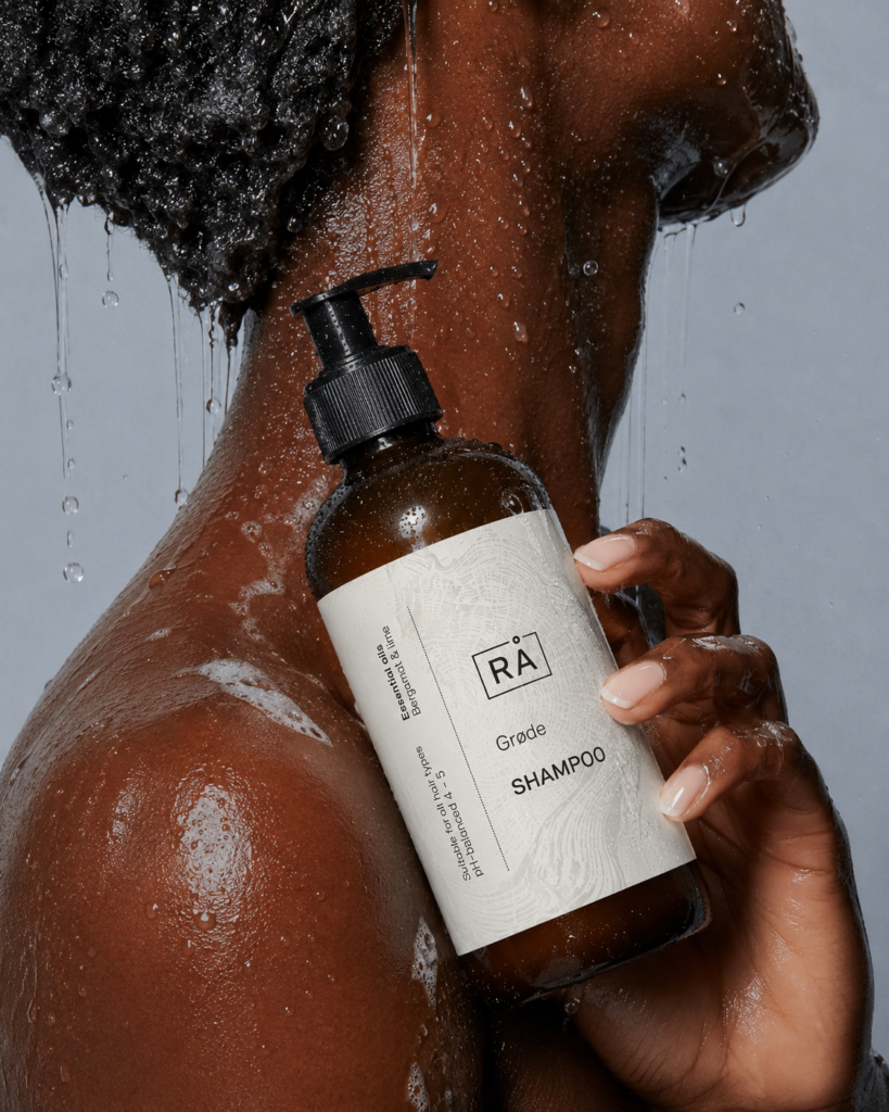 Kvinne holder RÅ Skincare grøde shampo i dusjen.