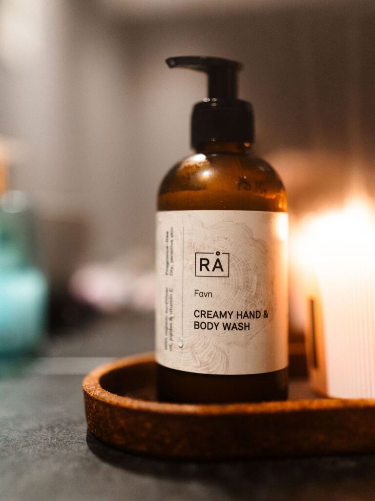 RÅ Favn Creamy Hand & Body Wash på et brett ved siden av et tent lys.