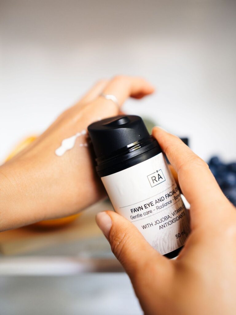 Favn Eye and Facial Cream fra RÅ Skincare påføres hånden for å vise kremens rike konsistens for tørr hud.