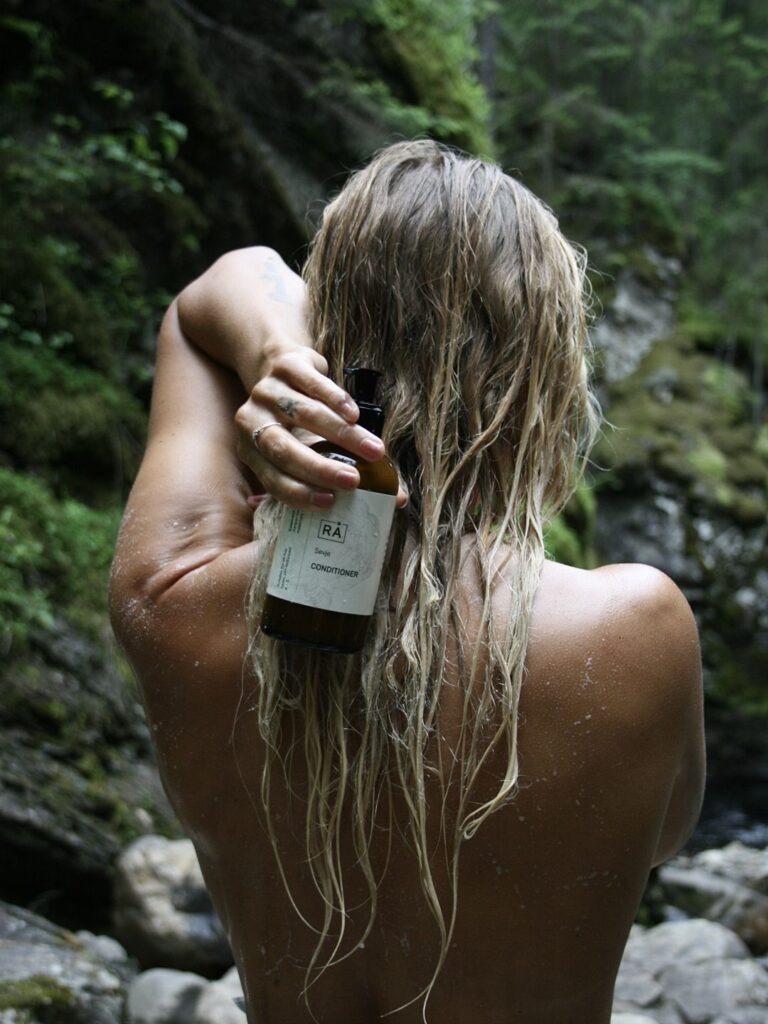 Dame med vått hår og balsam i håret holder grøde balsam fra rå skincare forran håret