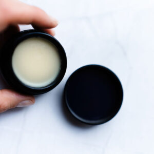 Bakuchiol correcting balm med åpen krukke som holdes av en dame hånd.