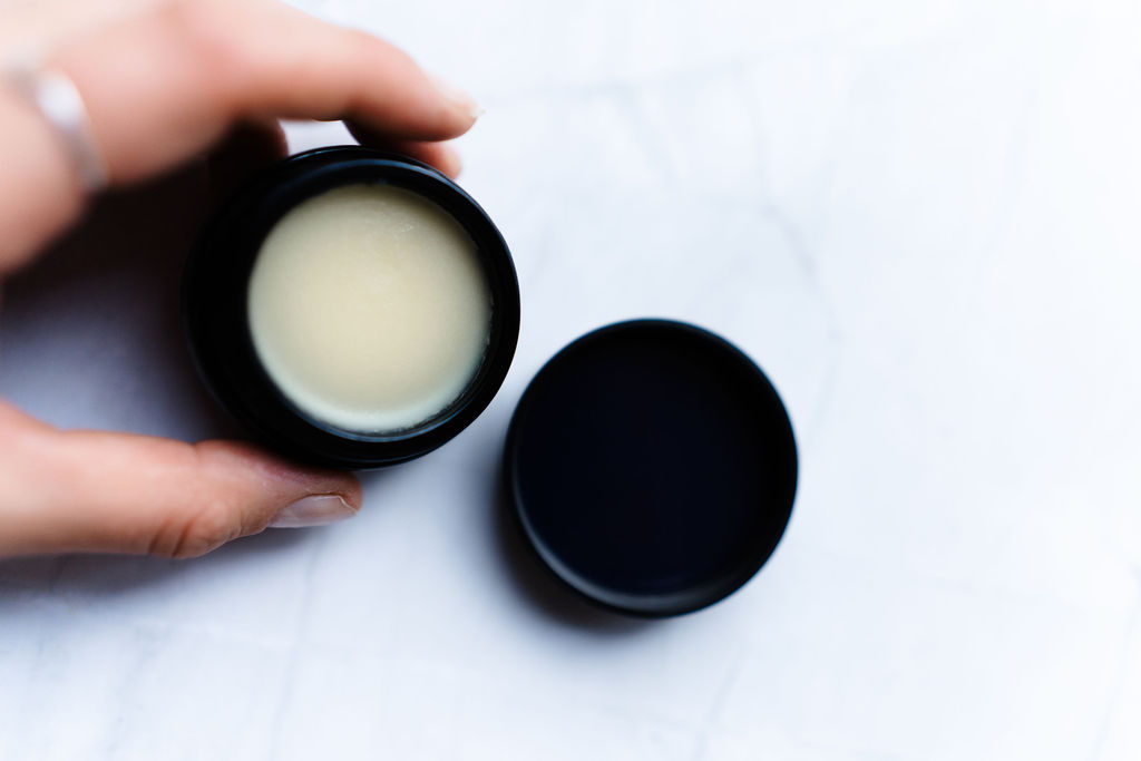 Bakuchiol correcting balm med åpen krukke som holdes av en dame hånd.