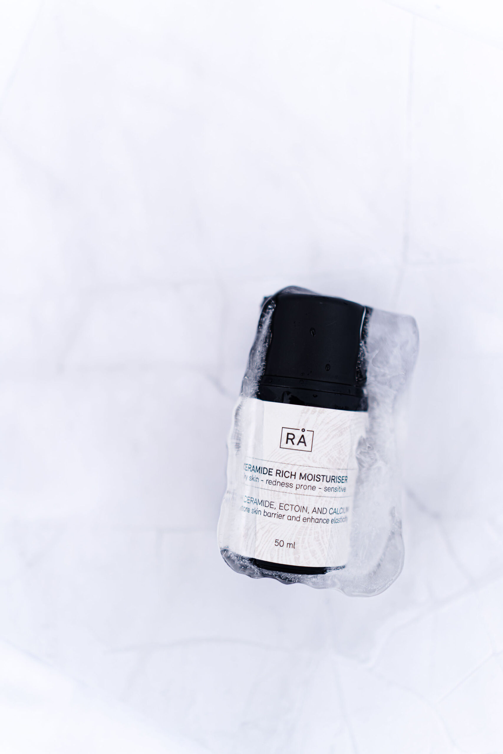 ceramide rich moisturiser inni isbit med lys bakgrunn