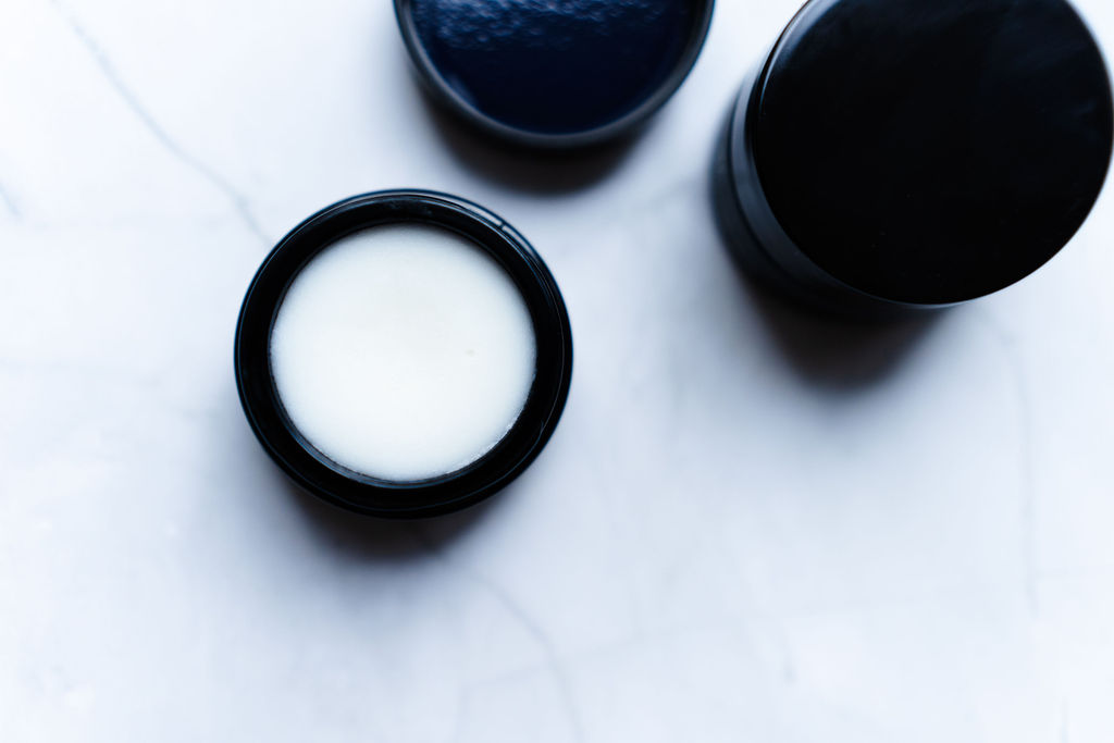 Bilde av en åpen krukkemes sos ceramide balm som viser balmens tykke konsistens og nærende egenskaper.