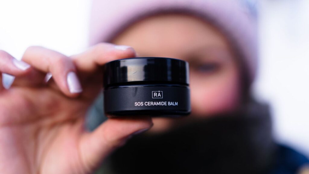 Dame holder krem i hånden ute i vinterkulden