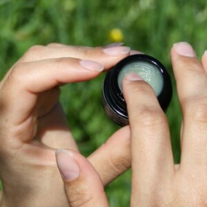 En finger tar ut rå ceramide lip balm fra krukken slik at du ser konsistensen på produktet tydelig