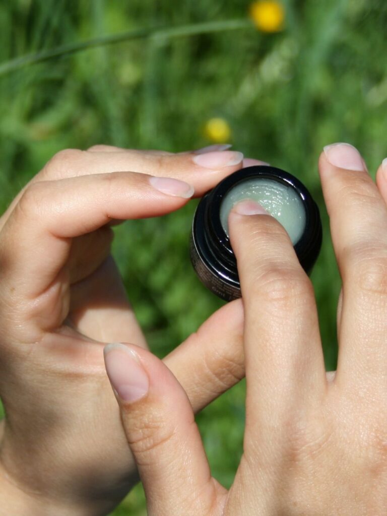 En finger tar ut rå ceramide lip balm fra krukken slik at du ser konsistensen på produktet tydelig