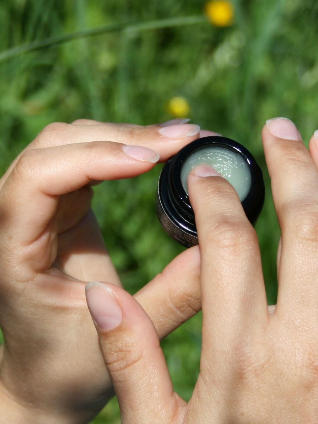 En finger tar ut rå ceramide lip balm fra krukken slik at du ser konsistensen på produktet tydelig