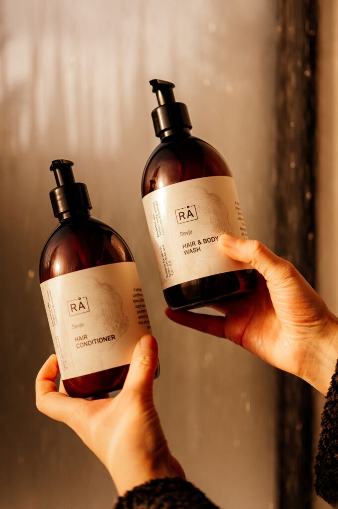 Sevje sjampo og balsam holdes under rennende vann i dusjen i speilglasshytten til furu of Norway