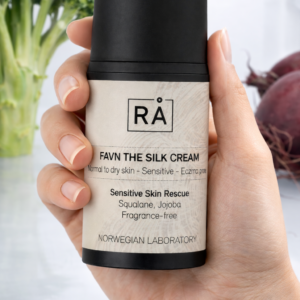 RÅ Skincare Favn the silk cream holdes i hånden inne i kjøleskap for å vise hvordan produktet skal oppbevares og få frem renhet.