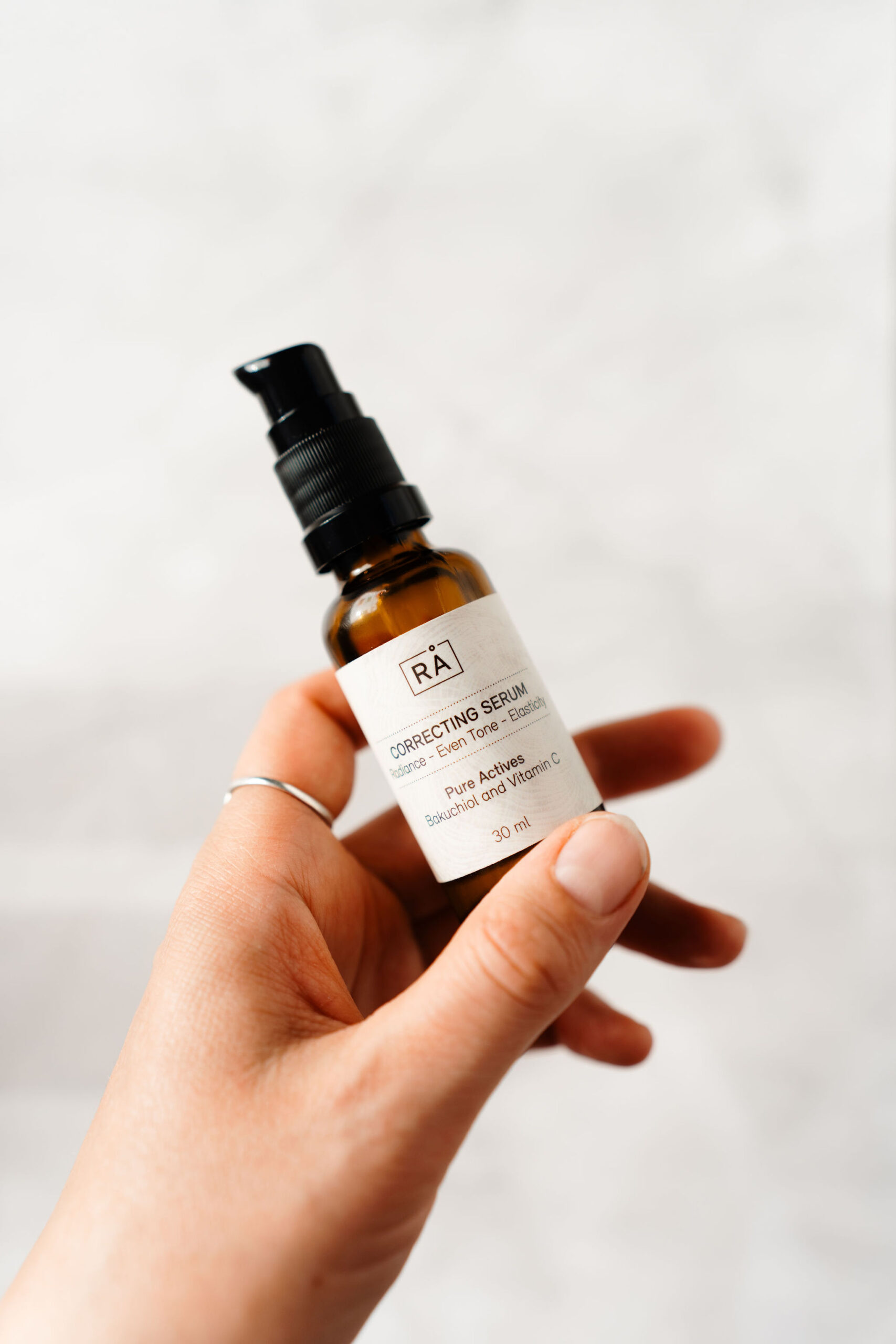 hånd som holder correcting serum med c-vitamin og bakuchiol