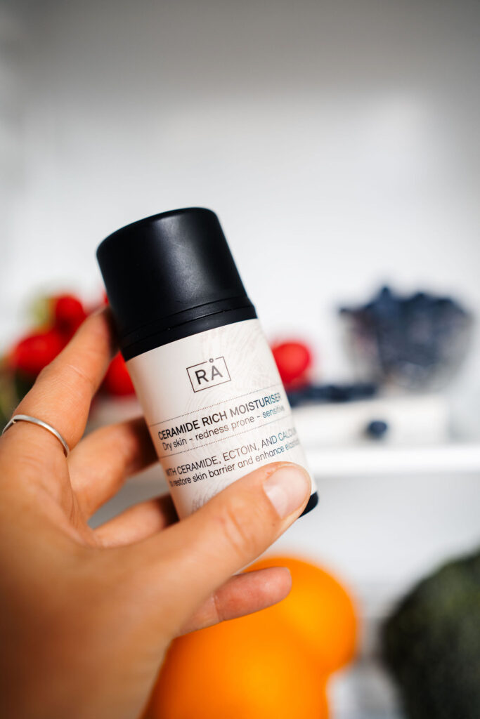 Ceramide rich moisturiser holdes inni kjøleskap med friske frukter i bakgrunnen for å vise oppbefaring av produktet