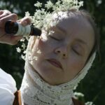 Tine Linea poserer med correcting serum ute i en blomstereng. Du ser tydelig arrene etter brannskaden på halsen