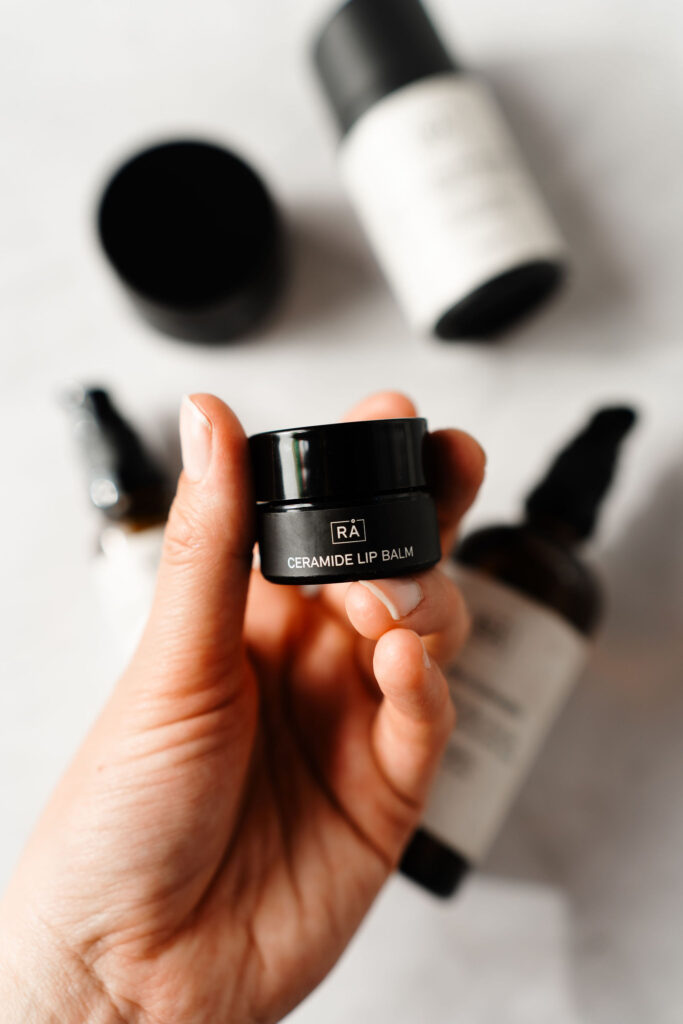 RÅ Skincare Ceramide lip balm holdes i hånden.