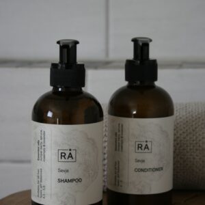 Sevje shampoo and conditioner stand on a wooden stool in the bathroom.