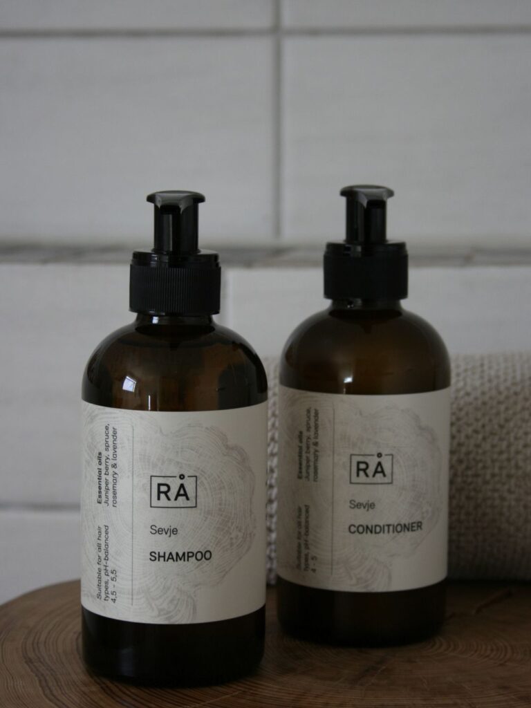 Sevje shampoo and conditioner stand on a wooden stool in the bathroom.
