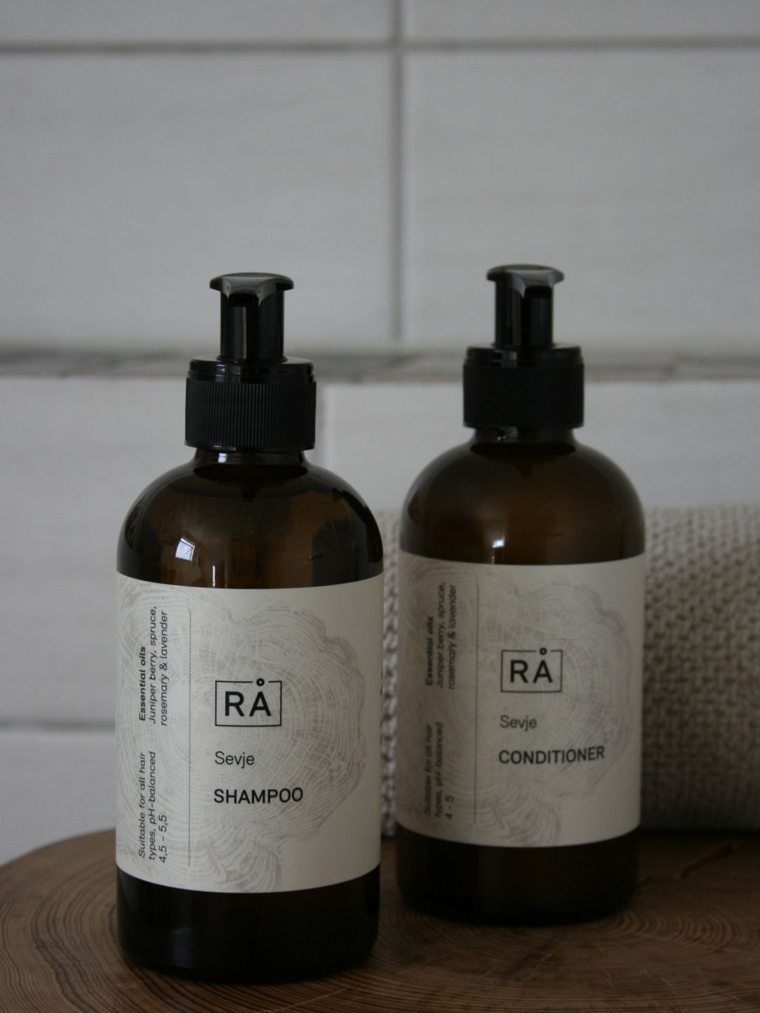 Sevje shampoo and conditioner stand on a wooden stool in the bathroom.