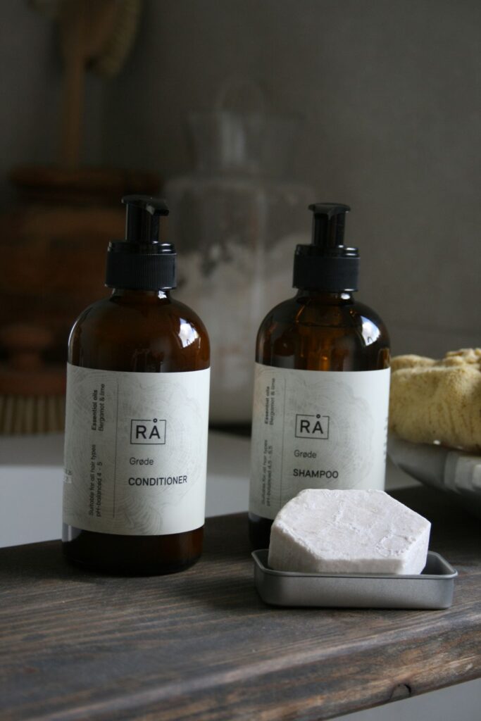 Grøde sjampo og balsam fra RÅ Skincare står på treplanke over badekaret